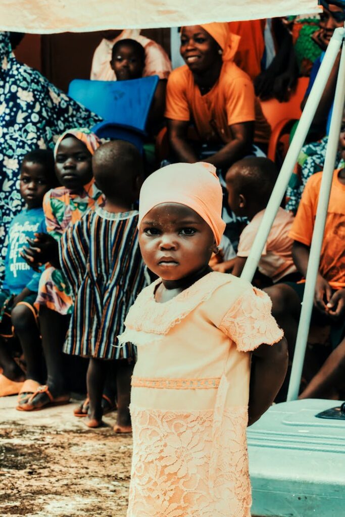 The Art of Drawing Readers In: Your attractive post title goes here A young girl stands amidst a community gathering in Nalerigu, Ghana, showcasing vibrant traditional attire and culture.
